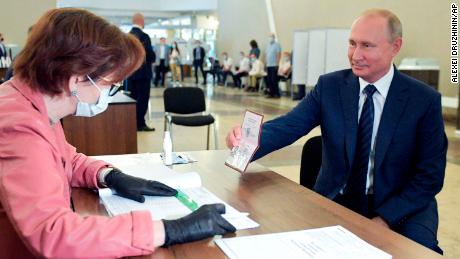 Russian President Vladimir Putin shows his passport to a member of an election commission as he arrives to take part in voting at a polling station in Moscow, Russia, Wednesday, July 1, 2020. The vote on the constitutional amendments that would reset the clock on Russian President Vladimir Putin&#39;s tenure and enable him to serve two more six-year terms is set to wrap up Wednesday. (Alexei Druzhinin, Sputnik, Kremlin Pool Photo via AP)